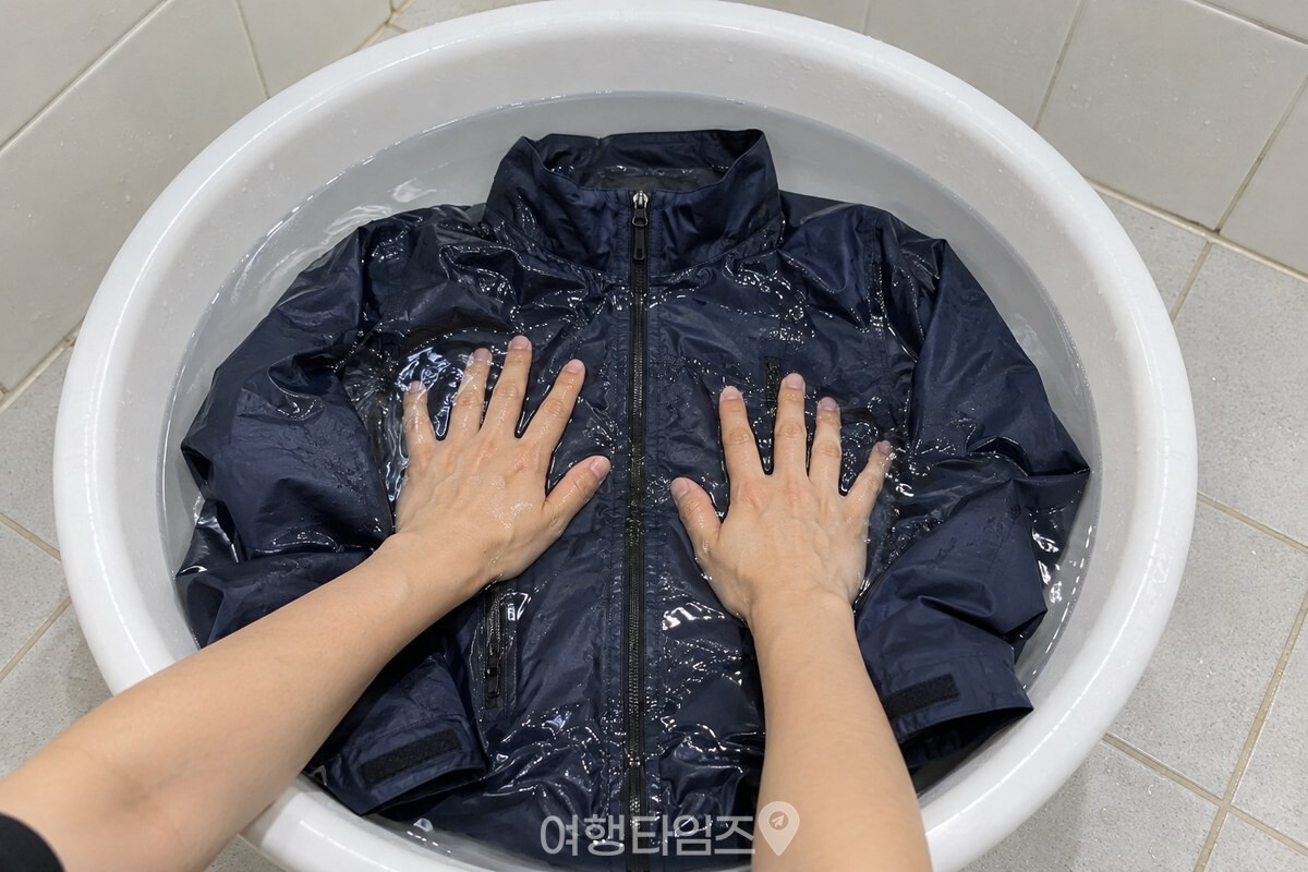 물에 펼친 등산 재킷을 손바닥으로 가볍게 누르는 손빨래 장면. / 기사 이해를 돕기 위한 생성형 이미지