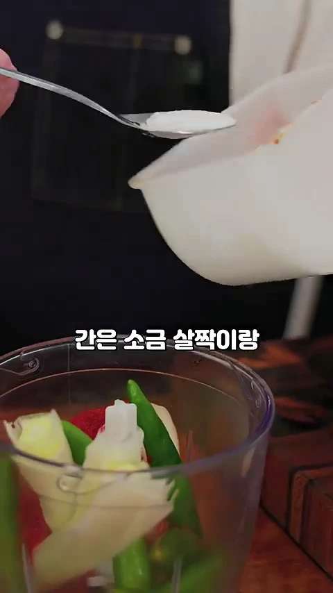 요리사가 투명한 믹서기 용기에 대파와 청양고추 등 채소를 넣고 숟가락으로 소금을 계량해 넣고 있는 모습