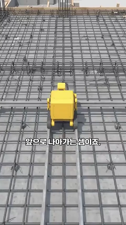 격자로 촘촘하게 배열된 철근 위에서 노란색 로봇이 레일을 따라 움직이며 작업을 수행하는 모습의 3D 그래픽 영상 화면.