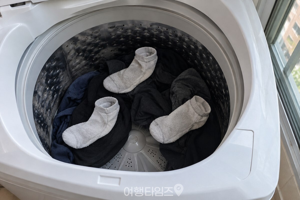 세탁물 위에 안팎으로 뒤집은 옅은 색 면양말 세 장을 나누어 올려 둔 통돌이 세탁기 모습. / 기사 이해를 돕기 위한 생성형 이미지