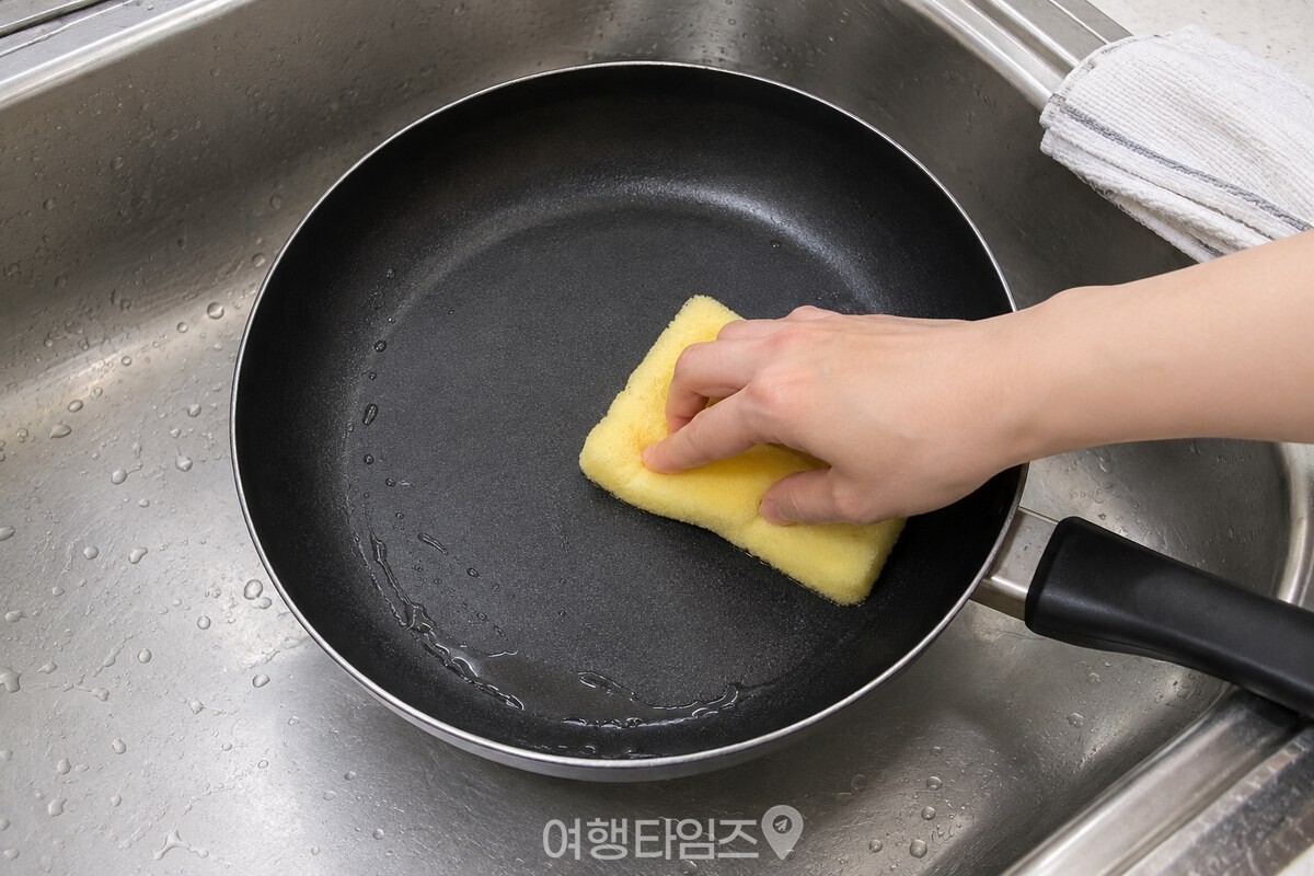 부드러운 노란 수세미로 헹군 코팅 팬 안쪽을 닦고 있는 모습. / 기사 이해를 돕기 위한 생성형 이미지