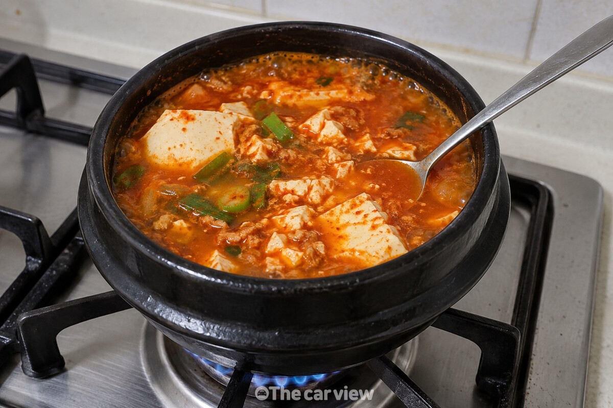 붉은 국물 속에서 순두부 덩어리가 숟가락 옆으로 부드럽게 풀어져 있다. / 기사 이해를 돕기 위한 생성형 이미지
