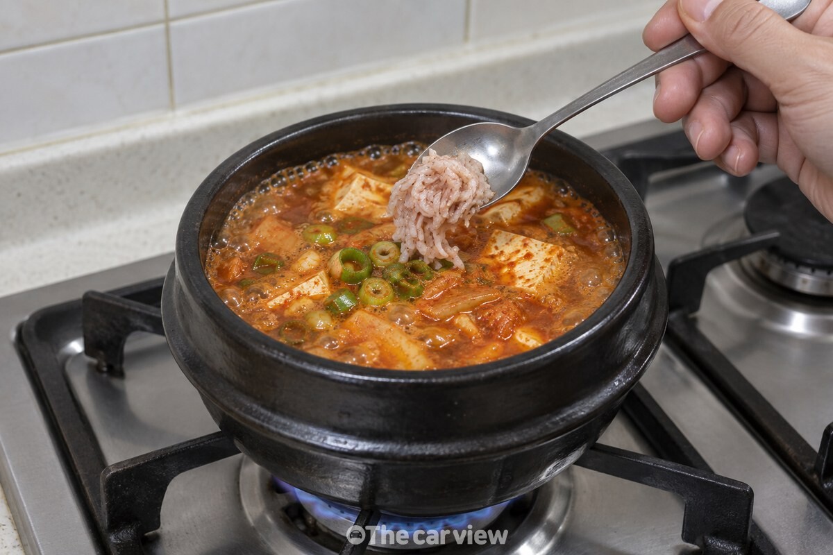 가장자리에 잔 기포가 올라오는 뚝배기 국물에 다진 새우젓 한 숟가락을 넣고 있다. / 기사 이해를 돕기 위한 생성형 이미지