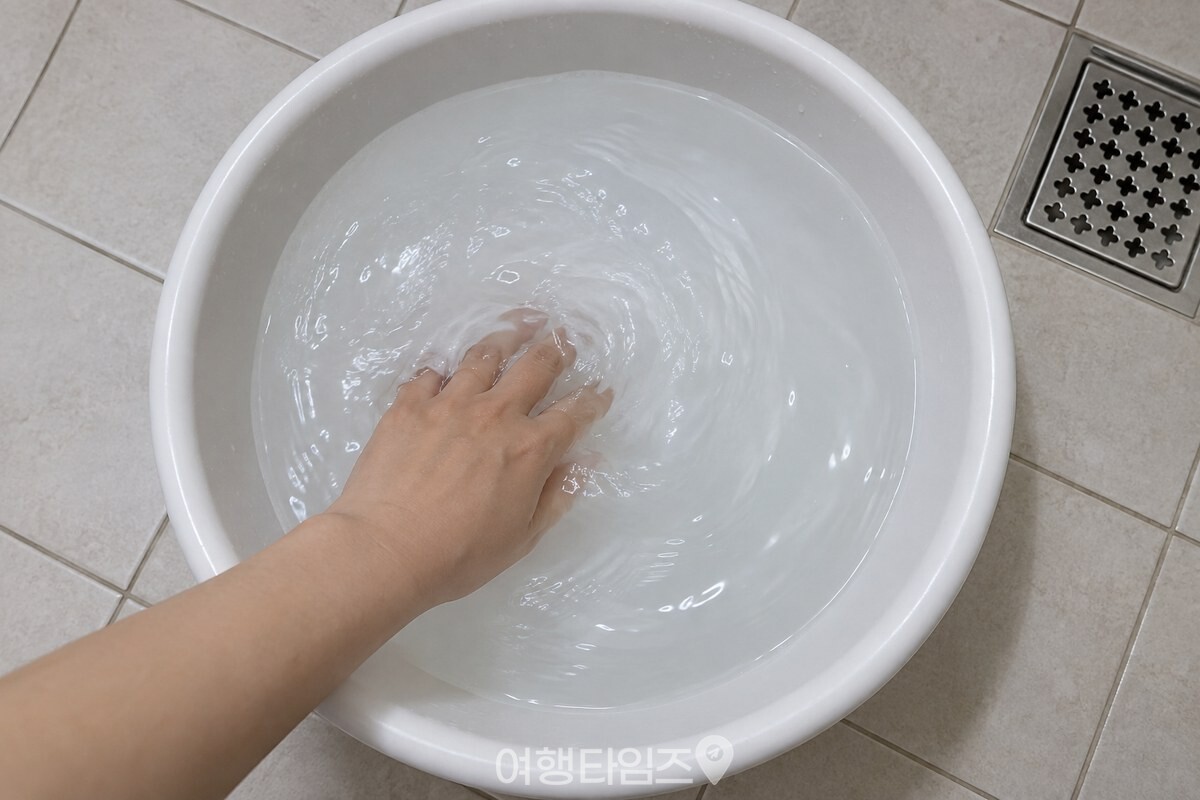 미지근한 물을 담은 흰 대야에 린스를 풀기 위해 손으로 물을 젓고 있다. / 기사 이해를 돕기 위한 생성형 이미지