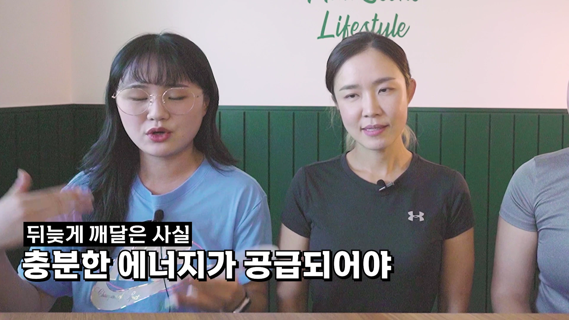 두 명의 여성이 앉아 대화를 나누는 모습으로, 왼쪽 여성은 안경을 쓰고 푸른색 티셔츠를 입었으며 오른쪽 여성은 검은색 운동복을 입고 있습니다. 화면 하단에는 흰색 자막으로 '뒤늦게 깨달은 사실, 충분한 에너지가 공급되어야'라는 문구가 표시되어 있습니다.