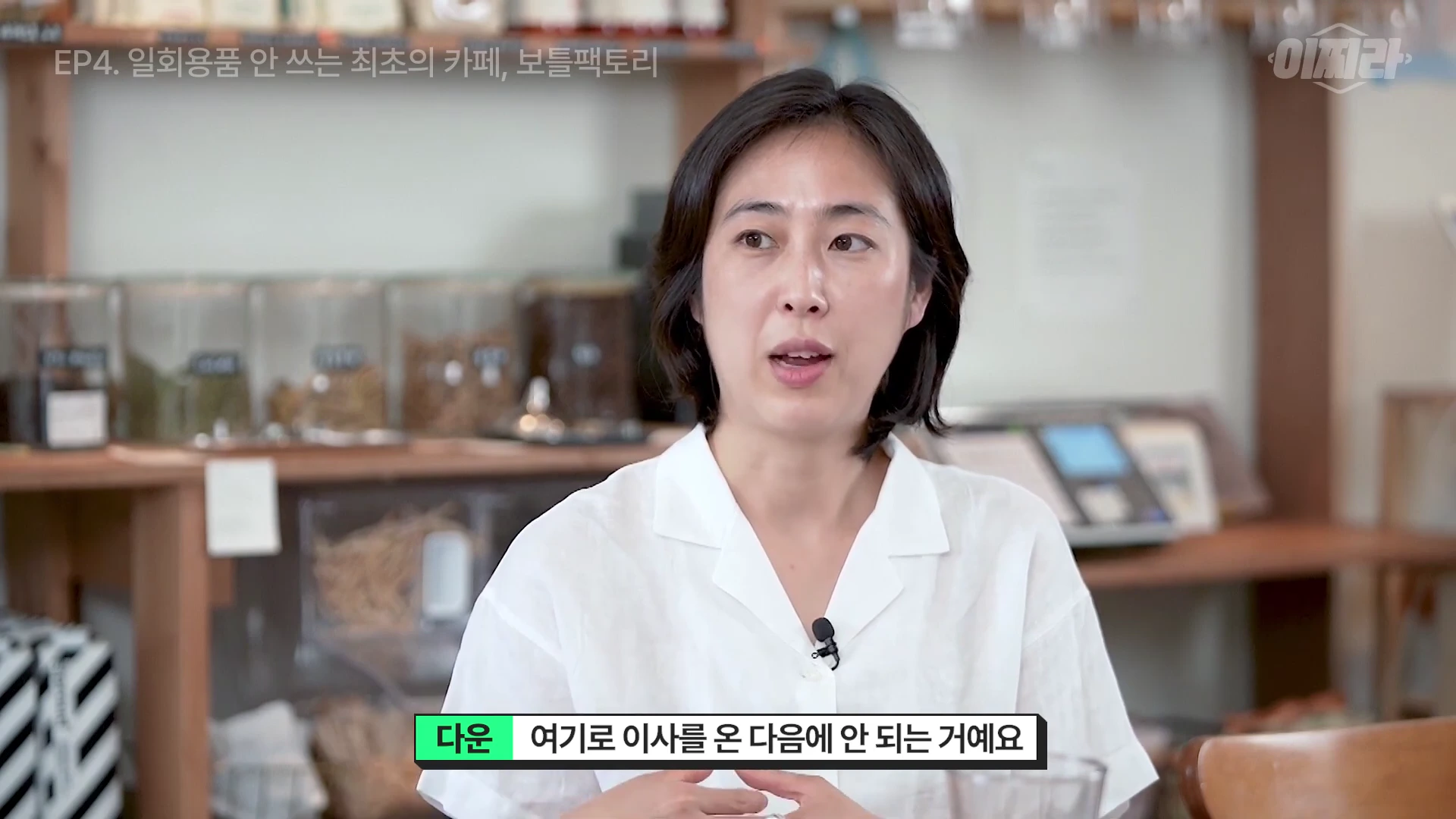 흰색 셔츠를 입은 단발머리 여성이 카페 실내를 배경으로 인터뷰하고 있는 모습