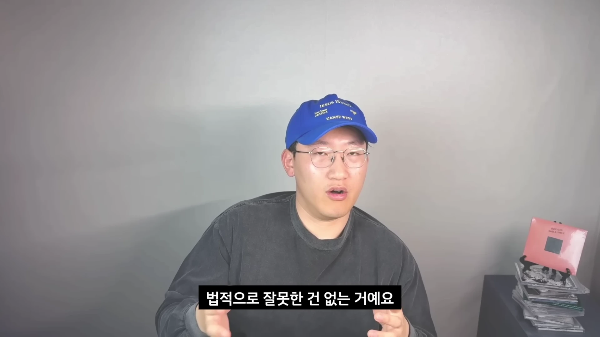파란색 야구 모자와 안경을 쓴 남성이 카메라를 보며 말을 하고 있고 화면 하단에는 '법적으로 잘못한 건 없는 거예요'라는 한국어 자막이 표시되어 있습니다.