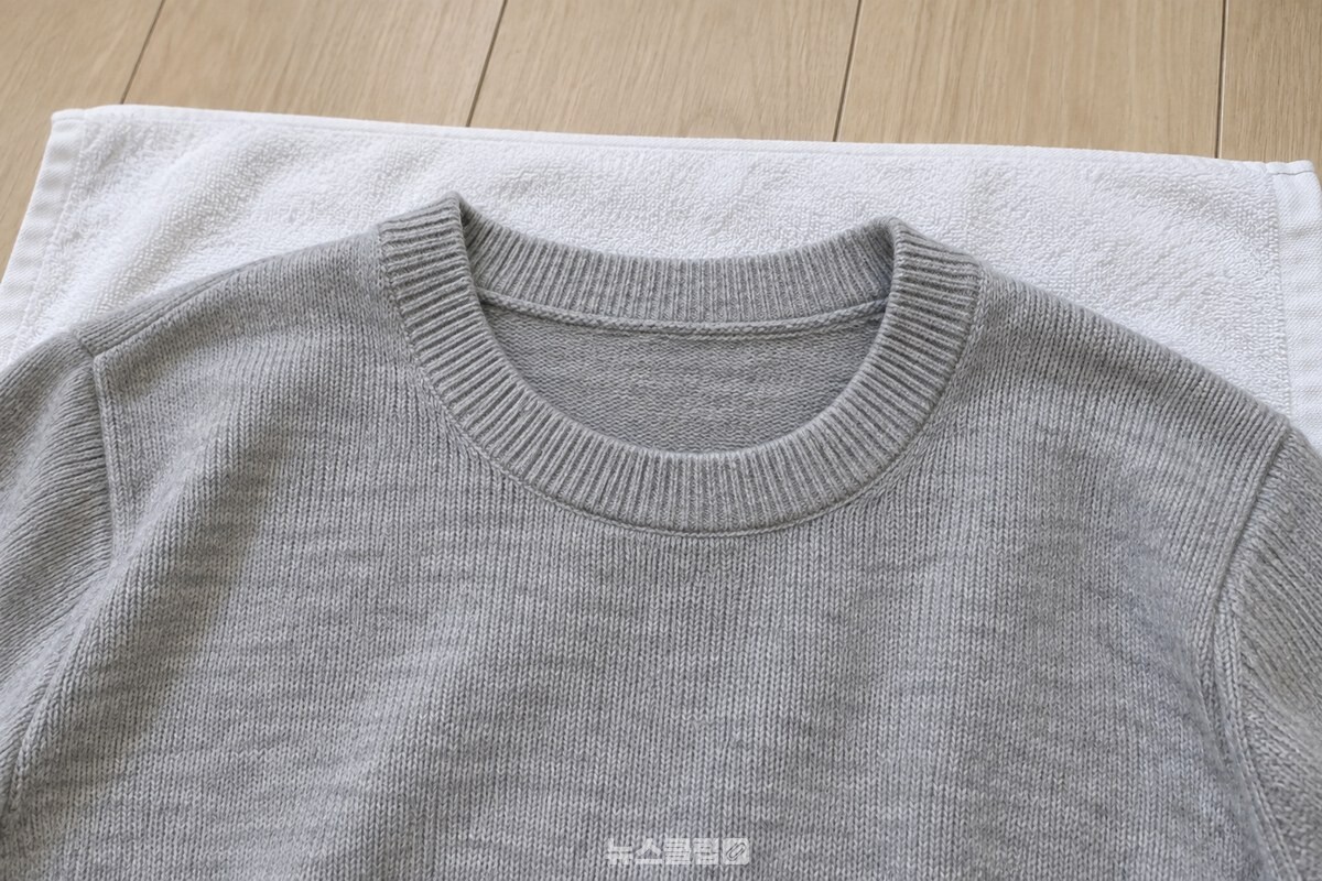 수건 위에 펼친 니트의 넓어진 목둘레와 고른 니트 조직이 보이는 모습. / 기사 이해를 돕기 위한 생성형 이미지