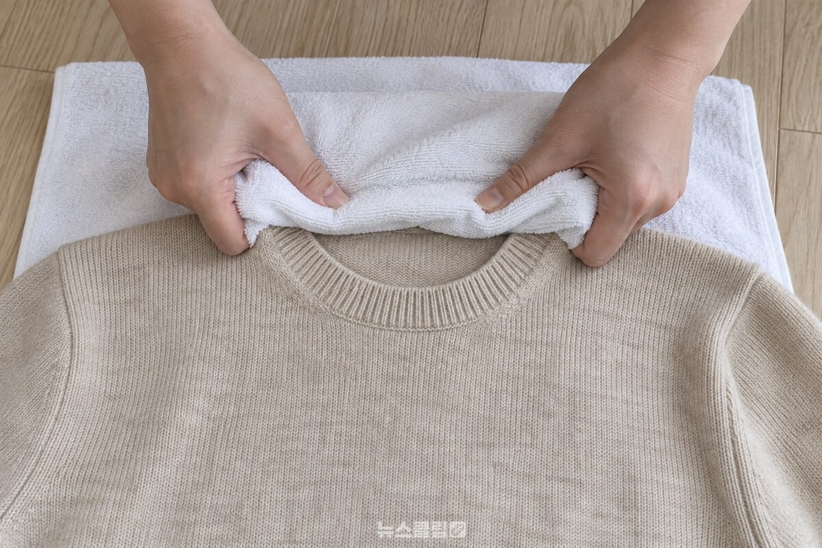 스팀을 쐰 니트 목선을 마른 수건 위로 양손이 안쪽으로 모아 잡는 모습. / 기사 이해를 돕기 위한 생성형 이미지