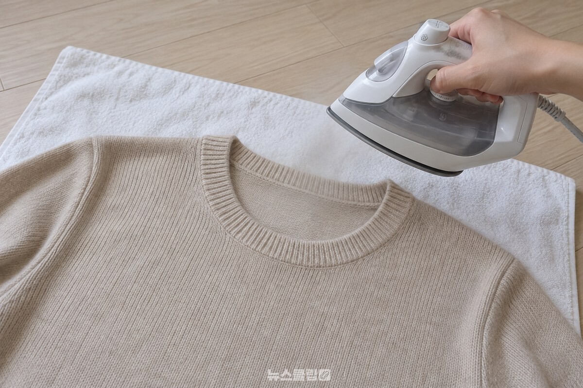 평평한 수건 위에 펼친 니트 목둘레에 스팀다리미를 거리를 두고 사용하는 모습. / 기사 이해를 돕기 위한 생성형 이미지