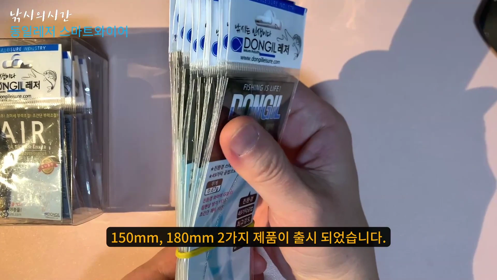 손에 여러 개의 동일레저 스마트 와이어 스위벨 채비 패키지가 묶여 있고 화면 하단에 150mm, 180mm 두 가지 제품 출시 안내 자막이 있는 영상 화면
