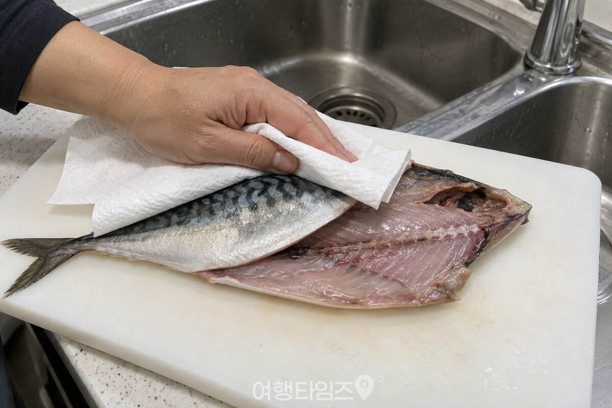 키친타월로 고등어의 껍질과 배 안쪽 물기를 눌러 닦고 있다. / 기사 이해를 돕기 위한 생성형 이미지