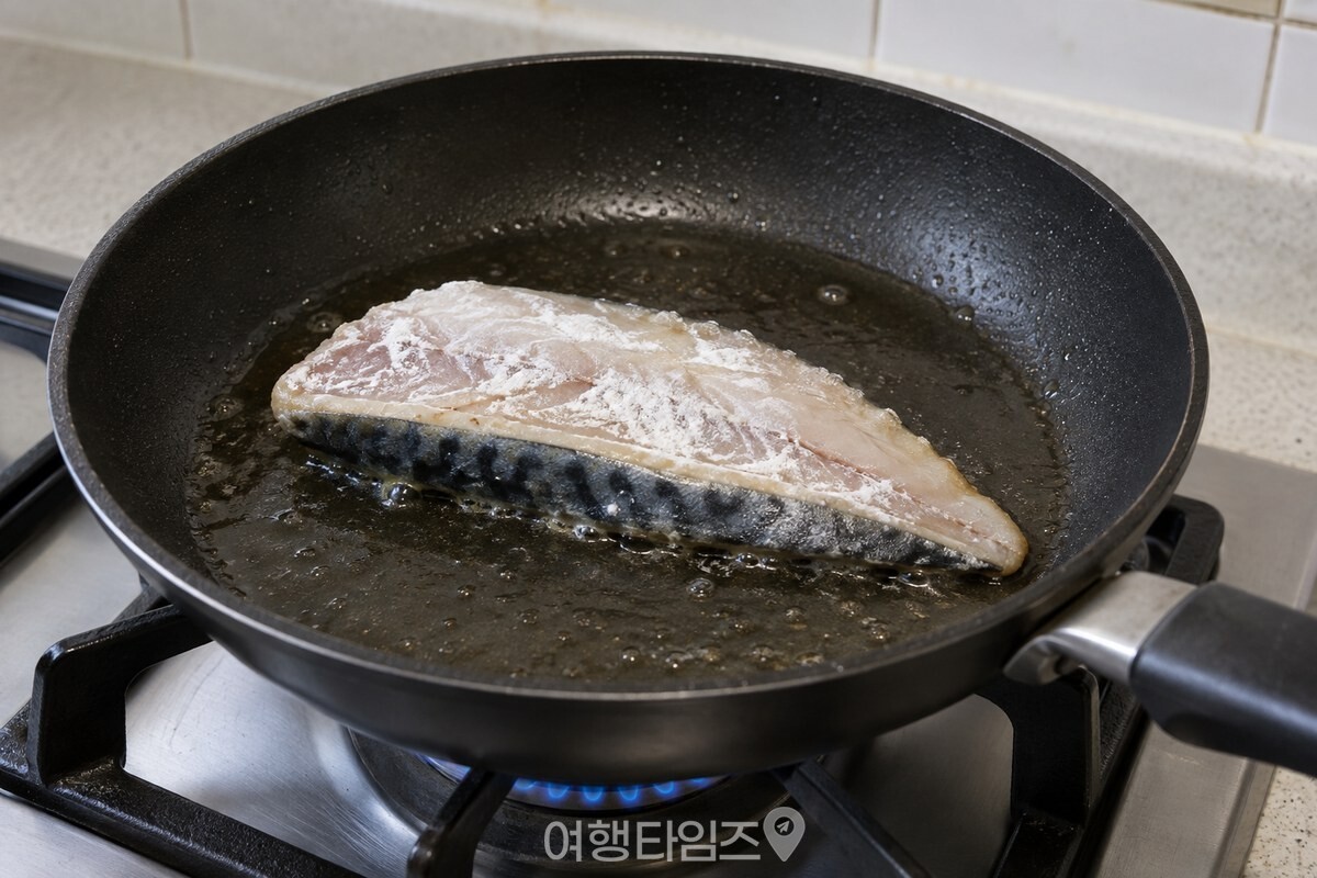 얇은 전분 옷을 입힌 고등어 토막이 팬에서 껍질 쪽부터 구워지고 있다. / 기사 이해를 돕기 위한 생성형 이미지