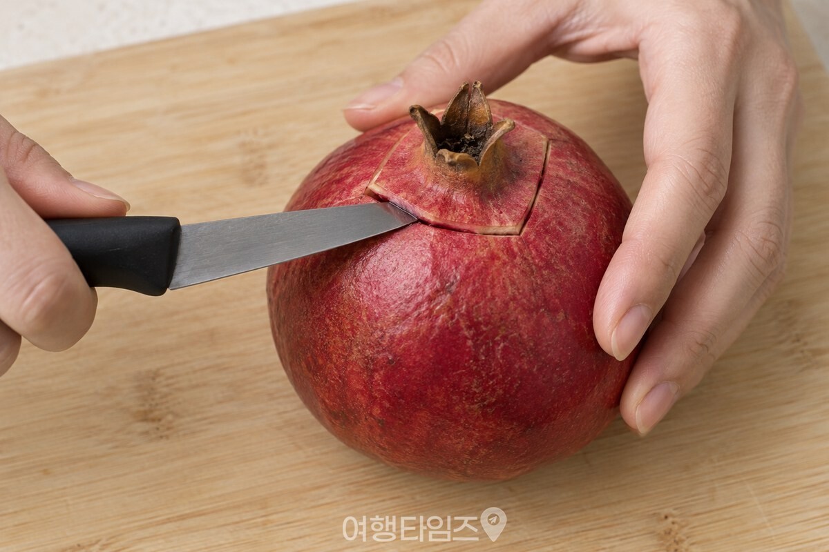 석류 꼭지 둘레의 껍질만 얕게 들어 올리는 과도와 손. / 기사 이해를 돕기 위한 생성형 이미지