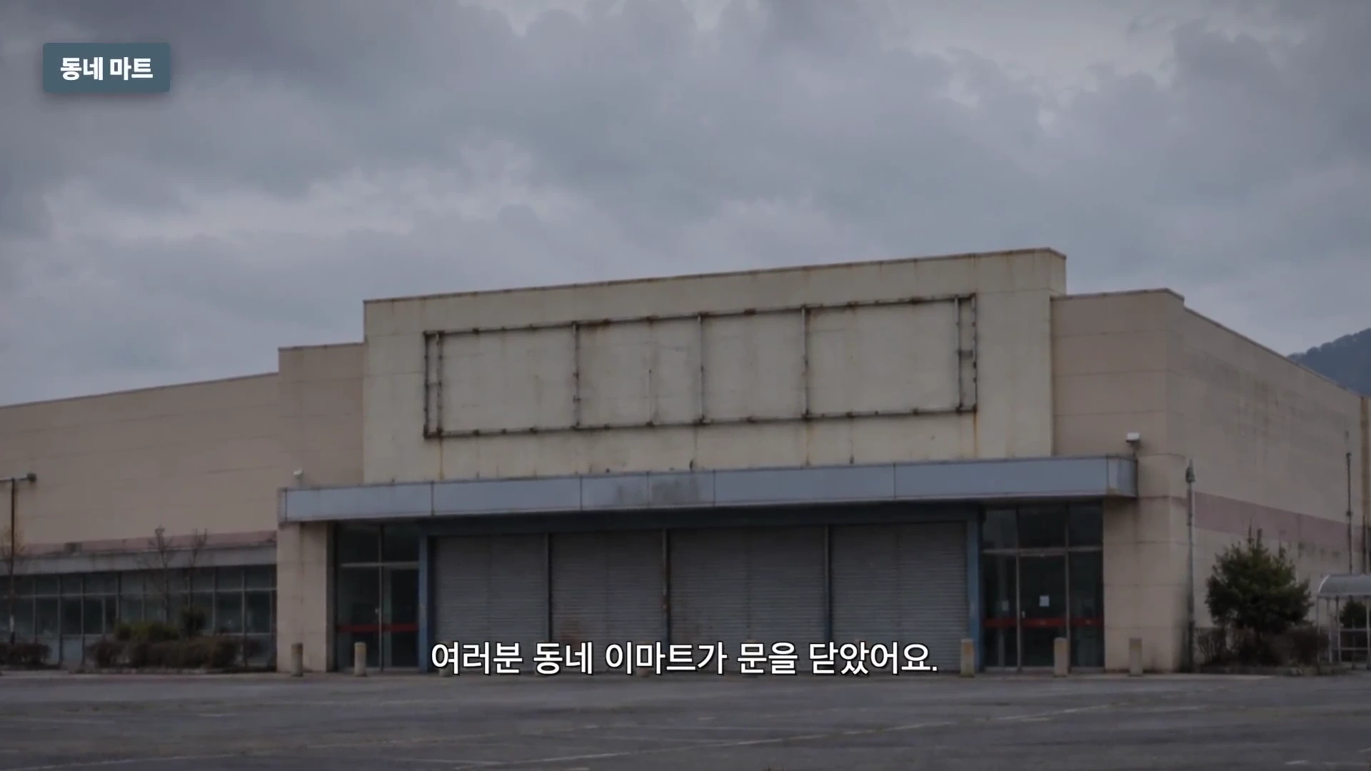 간판이 제거된 텅 빈 대형 마트 건물의 외부 모습과 넓은 주차장.