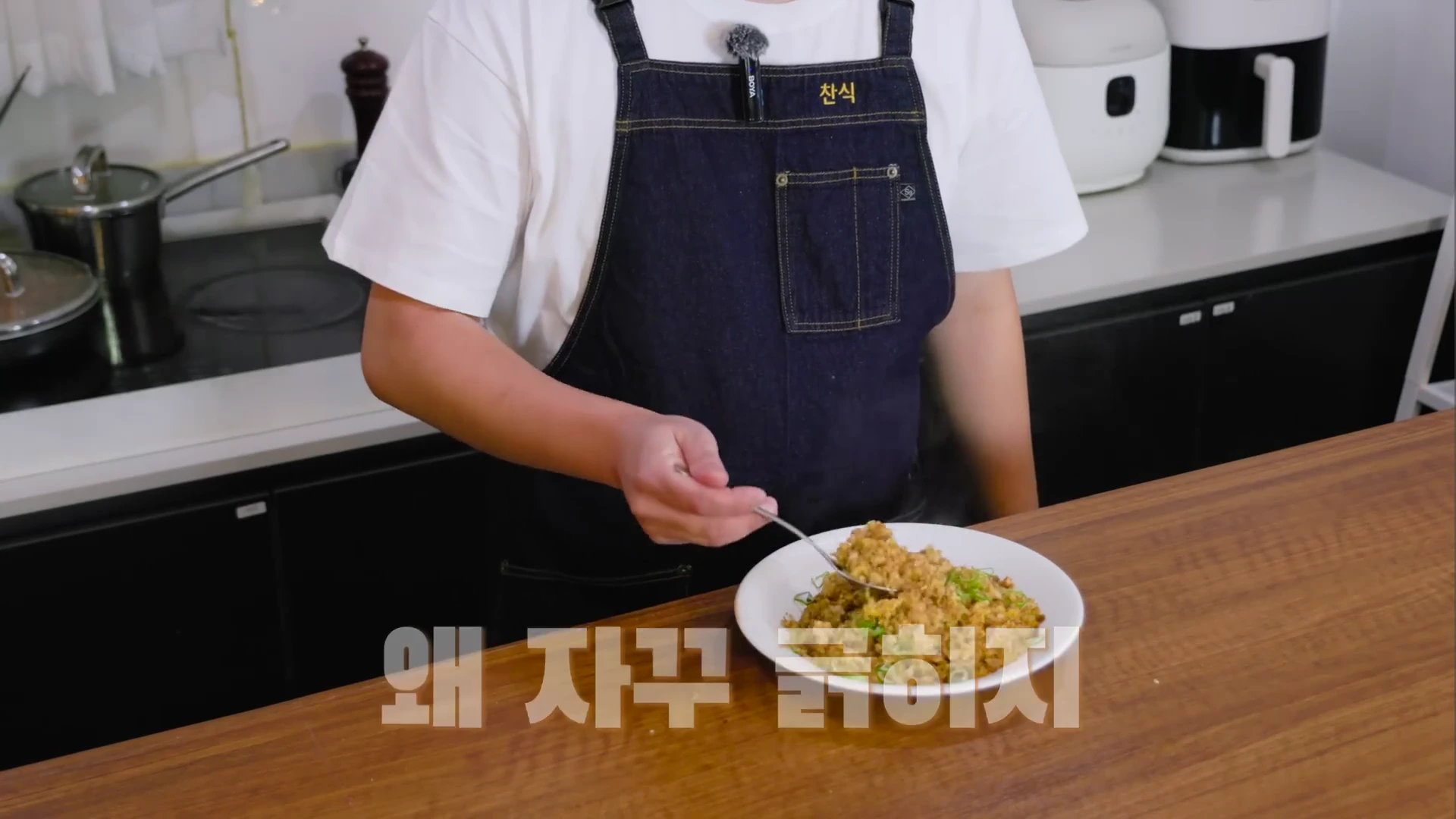 앞치마를 두른 요리사가 흰 접시에 담긴 볶음밥을 숟가락으로 떠 올리고 있는 모습
