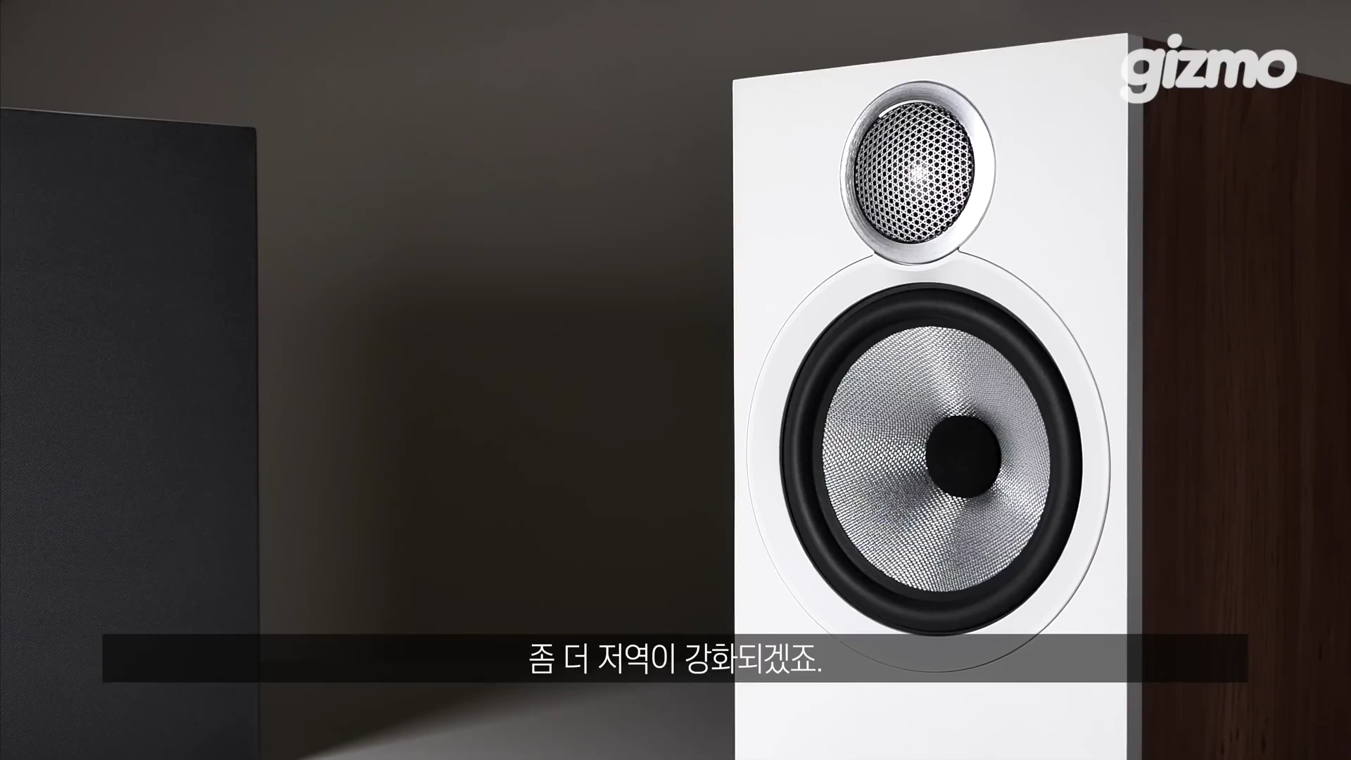 흰색 전면 패널과 메탈 질감의 우퍼 및 트위터 유닛이 드러난 북쉘프 스피커의 클로즈업 샷입니다.