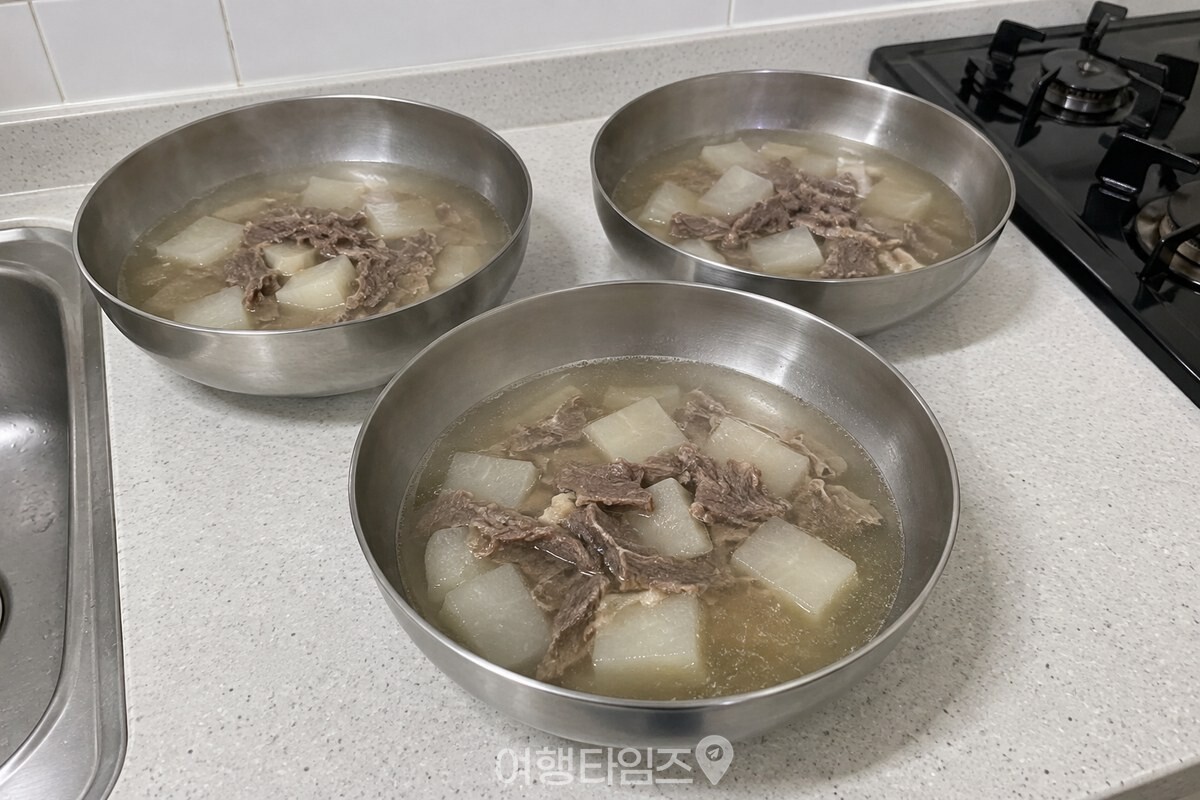 가스레인지에서 막 옮긴 국을 얕은 스테인리스 그릇 세 개에 나눠 담아 식히는 모습. / 기사 이해를 돕기 위한 생성형 이미지