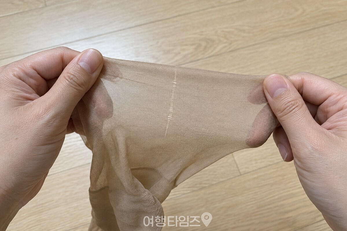 손가락 끝으로 펼친 스타킹 원단에 가는 세로 올 하나가 보인다. / 기사 이해를 돕기 위한 생성형 이미지