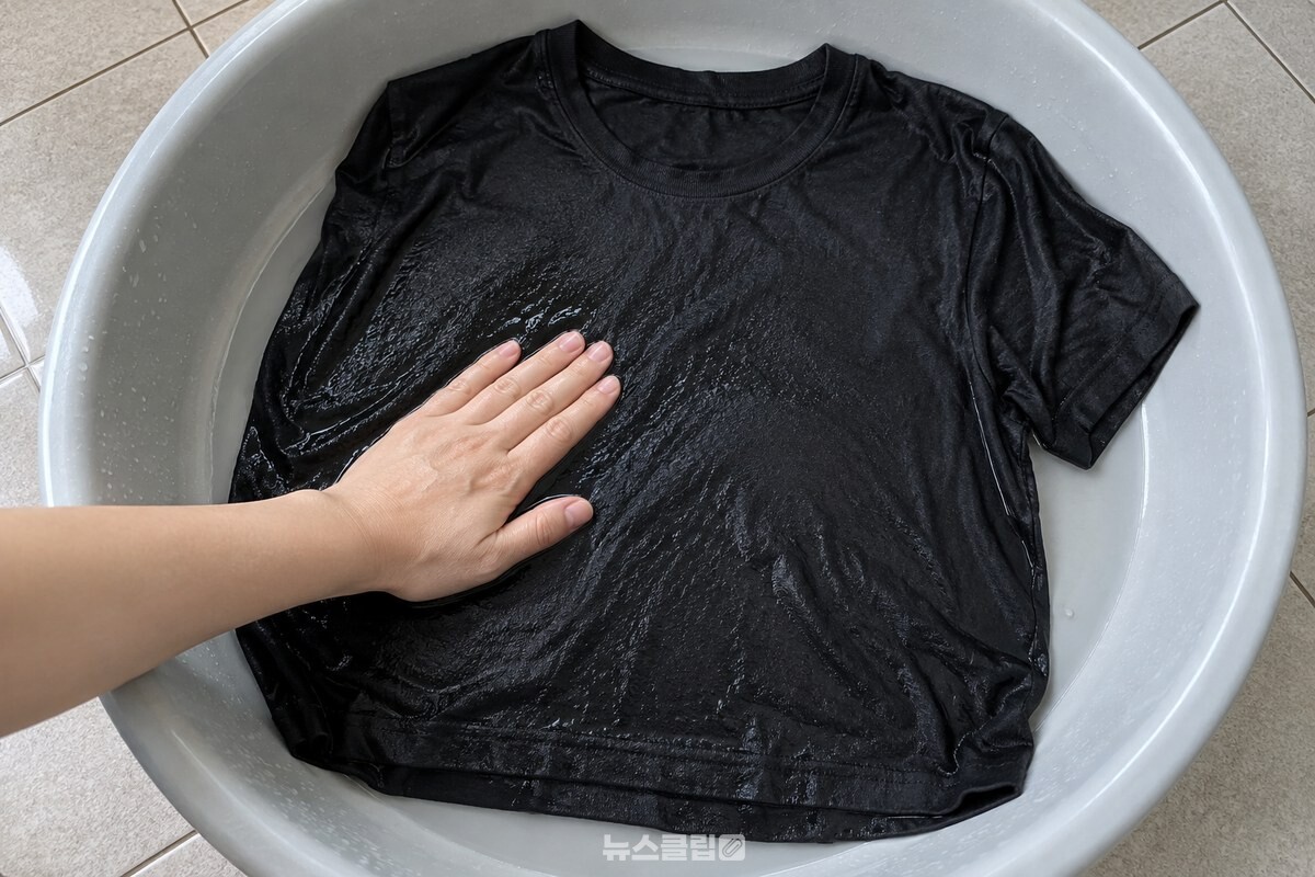 검은 면 티셔츠의 매끈하게 젖은 앞면을 손으로 펴 보이는 모습. / 기사 이해를 돕기 위한 생성형 이미지