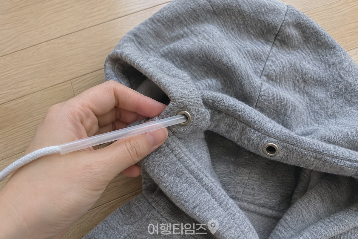 모자 천을 펴 잡고 빨대를 끈 통로로 밀어 넣는 모습. / 기사 이해를 돕기 위한 생성형 이미지