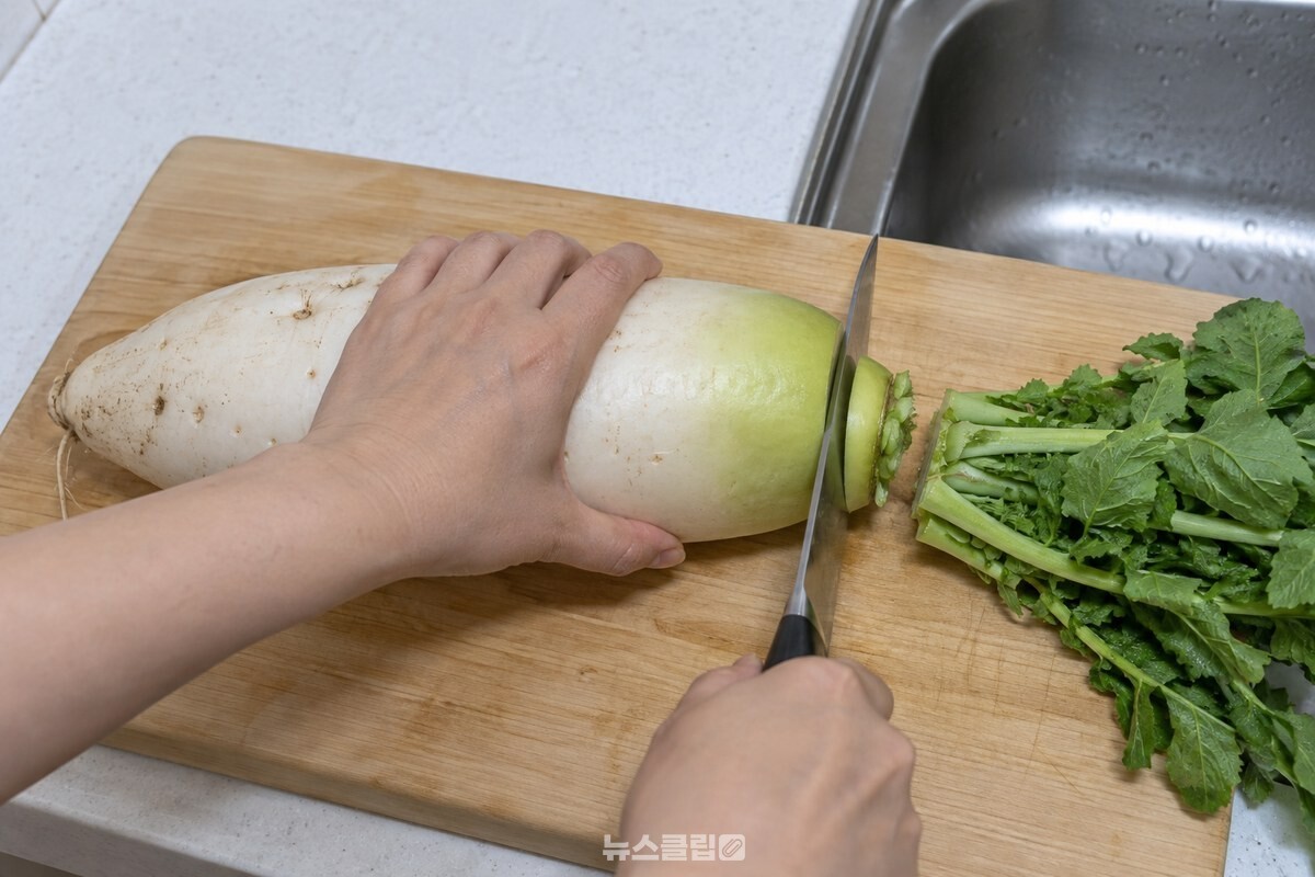 도마 위 가을 무의 무청을 어깨에서 조금 남기고 자르는 모습. / 기사 이해를 돕기 위한 생성형 이미지