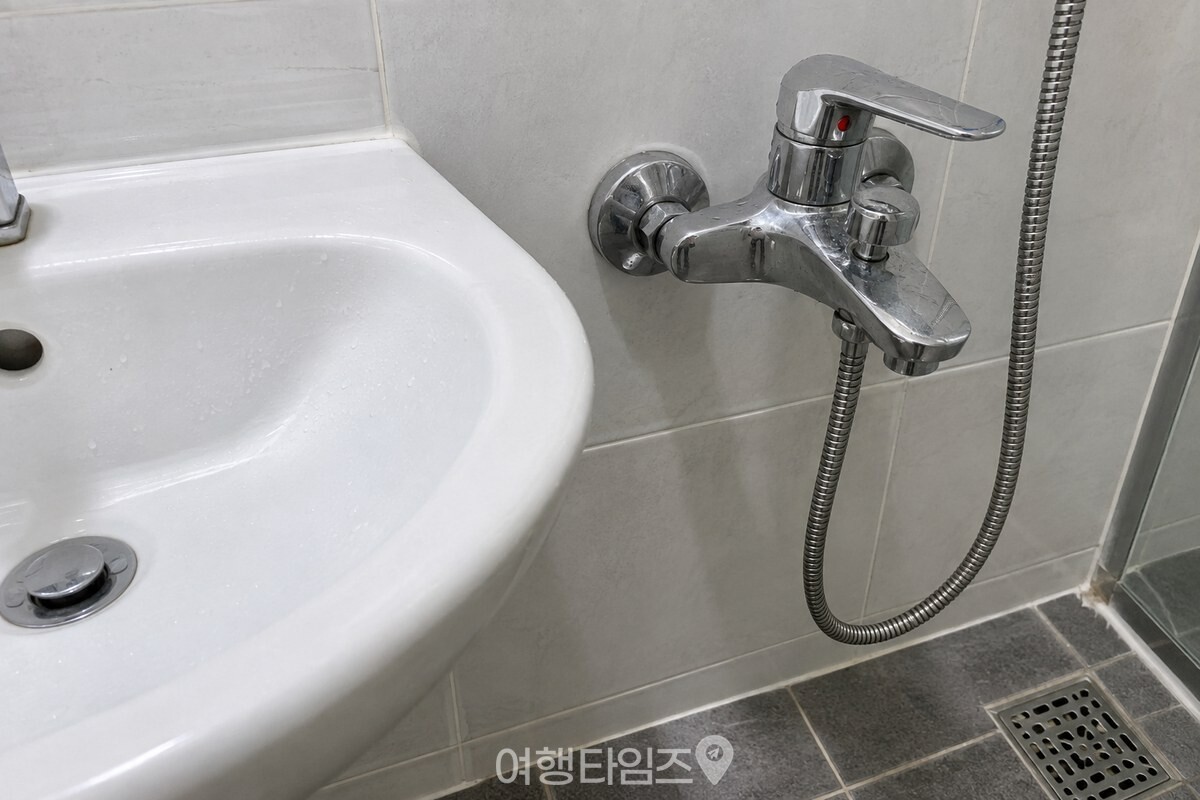 욕실 세면대 옆에서 온수 쪽으로 끝까지 돌린 샤워 수전을 가까이에서 본 모습. / 기사 이해를 돕기 위한 생성형 이미지