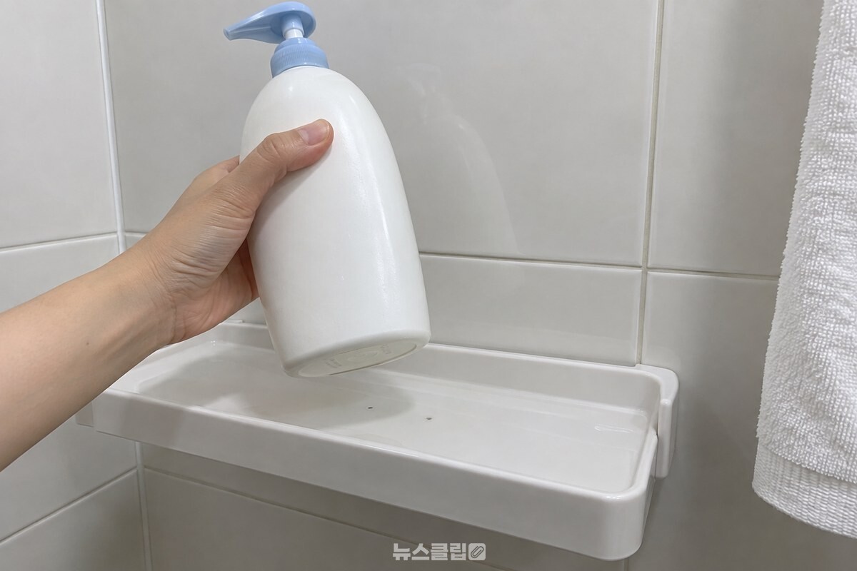 샴푸통을 들어 올린 뒤 선반의 작은 검은 자국과 통 바닥을 가까이 보여 준 모습. / 기사 이해를 돕기 위한 생성형 이미지