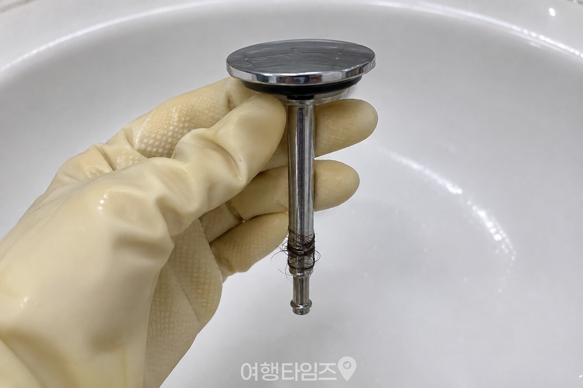 세면대 배수구에서 뺀 팝업 마개 축에 머리카락이 감겨 있는 근접 모습 / 기사 이해를 돕기 위한 생성형 이미지