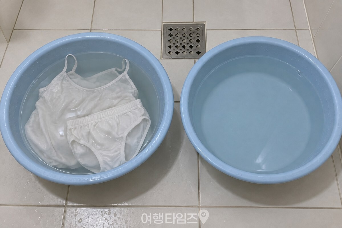 욕실 바닥의 두 대야에 속옷 세탁물과 헹굼물을 미리 나누어 받은 모습. / 기사 이해를 돕기 위한 생성형 이미지