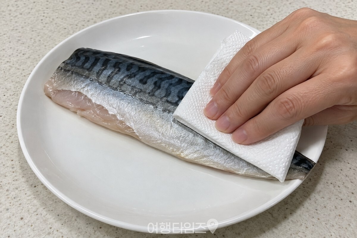 깨끗한 키친타월로 고등어 껍질과 가장자리의 물기를 눌러 닦는 손. / 기사 이해를 돕기 위한 생성형 이미지