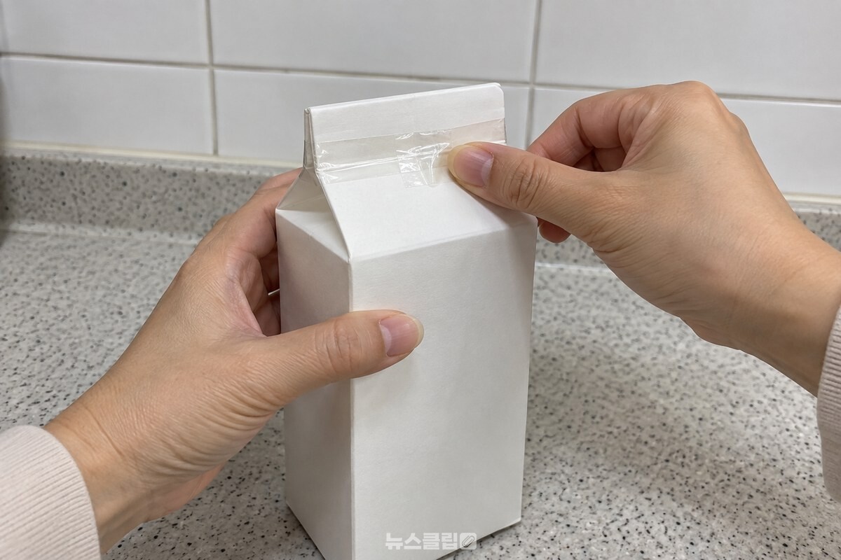 식은 기름을 담은 우유팩의 입구를 원래 접힌 선대로 접고 테이프로 한 바퀴 감아 막는 모습이다. / 기사 이해를 돕기 위한 생성형 이미지