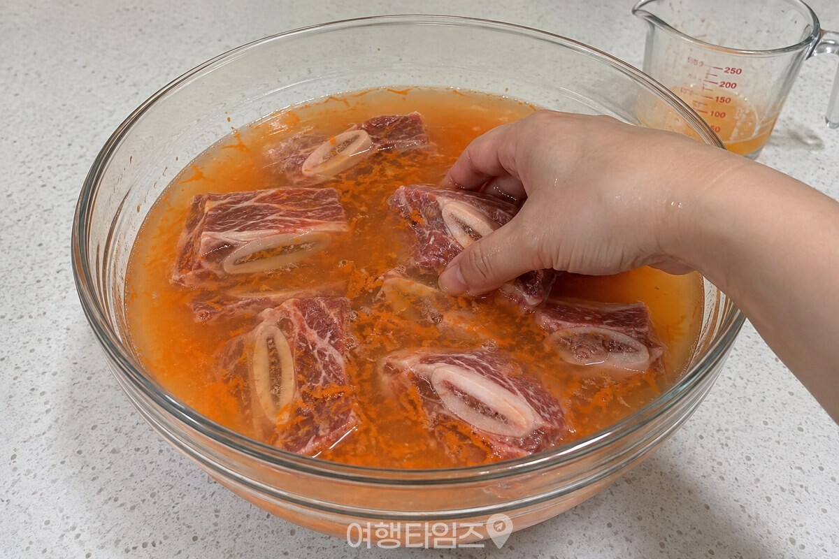 당근즙과 물에 잠긴 갈비를 손으로 한 번 뒤집는 모습. / 기사 이해를 돕기 위한 생성형 이미지