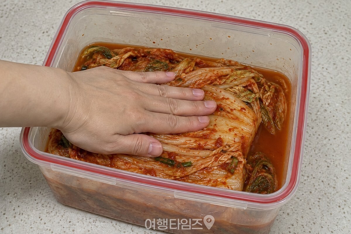 손바닥으로 김치 한 켜를 눌러 국물 아래로 가라앉히는 모습. / 기사 이해를 돕기 위한 생성형 이미지