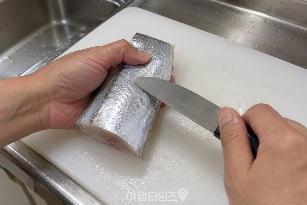 손질한 갈치 토막의 은색 껍질을 칼등으로 가볍게 긁는 모습. / 기사 이해를 돕기 위한 생성형 이미지
