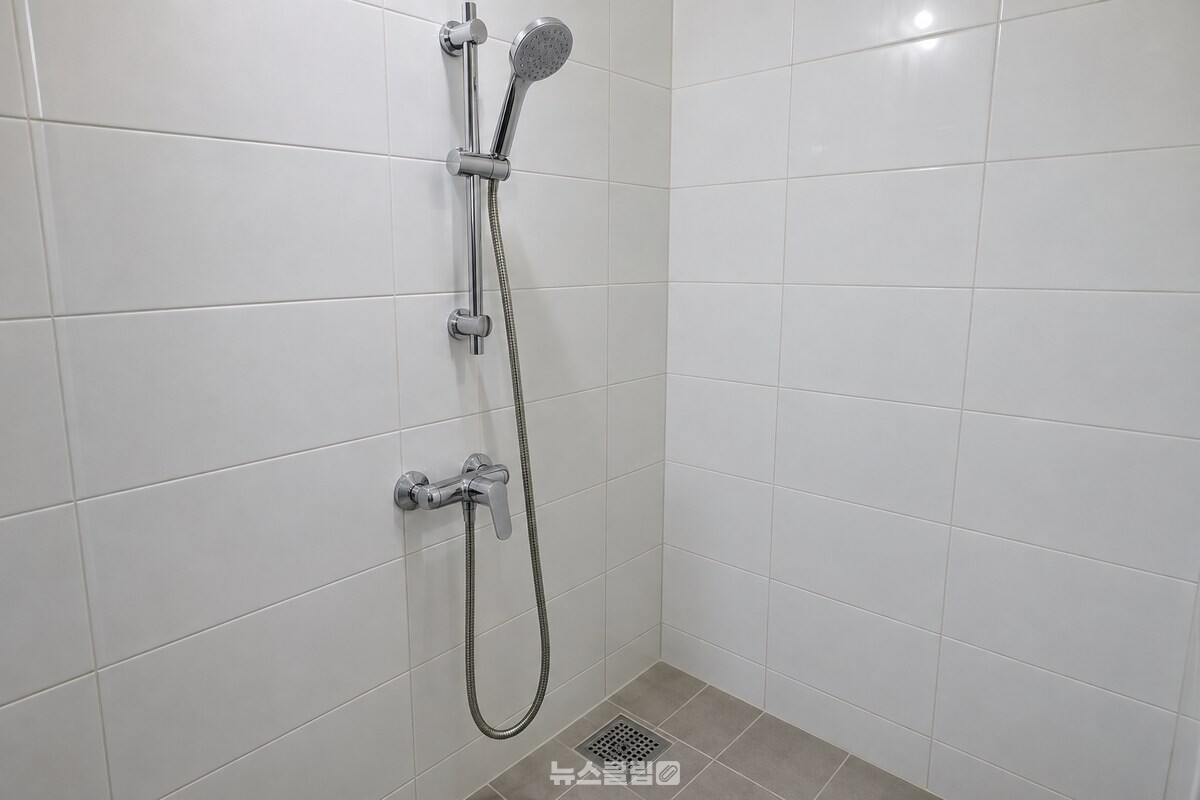 높은 거치대에 샤워기 헤드를 끼워 호스가 바닥에 닿지 않게 한 모습. / 기사 이해를 돕기 위한 생성형 이미지