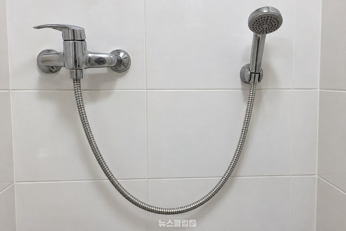벽 쪽으로 U자 모양으로 꺾여 걸린 샤워기 호스의 낮은 부분. / 기사 이해를 돕기 위한 생성형 이미지