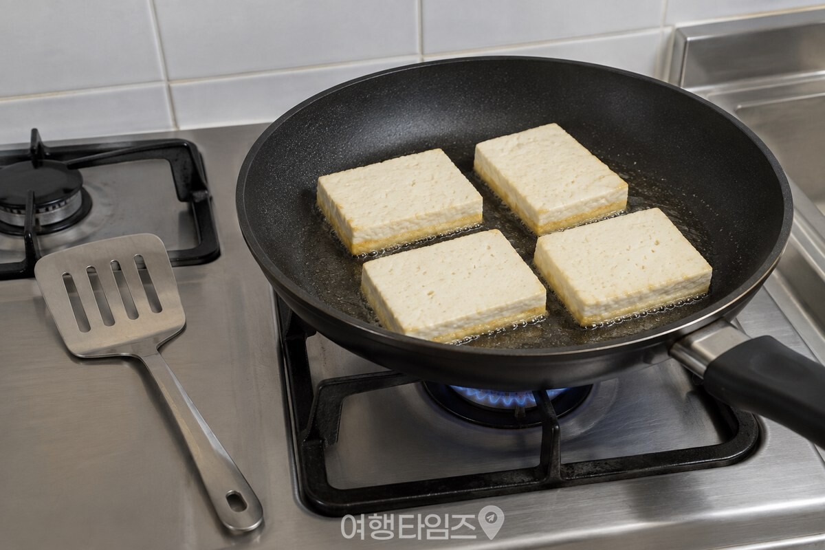 팬 가장자리가 노랗게 익은 두부를 건드리지 않고 두는 중불 조리 장면. / 기사 이해를 돕기 위한 생성형 이미지