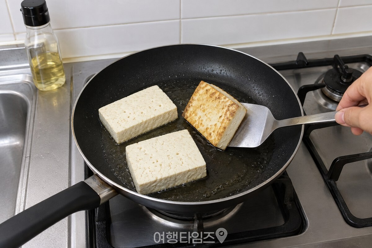 중불의 프라이팬에서 한 면이 노릇해진 두부 조각을 뒤집개로 한 번 뒤집는 모습. / 기사 이해를 돕기 위한 생성형 이미지
