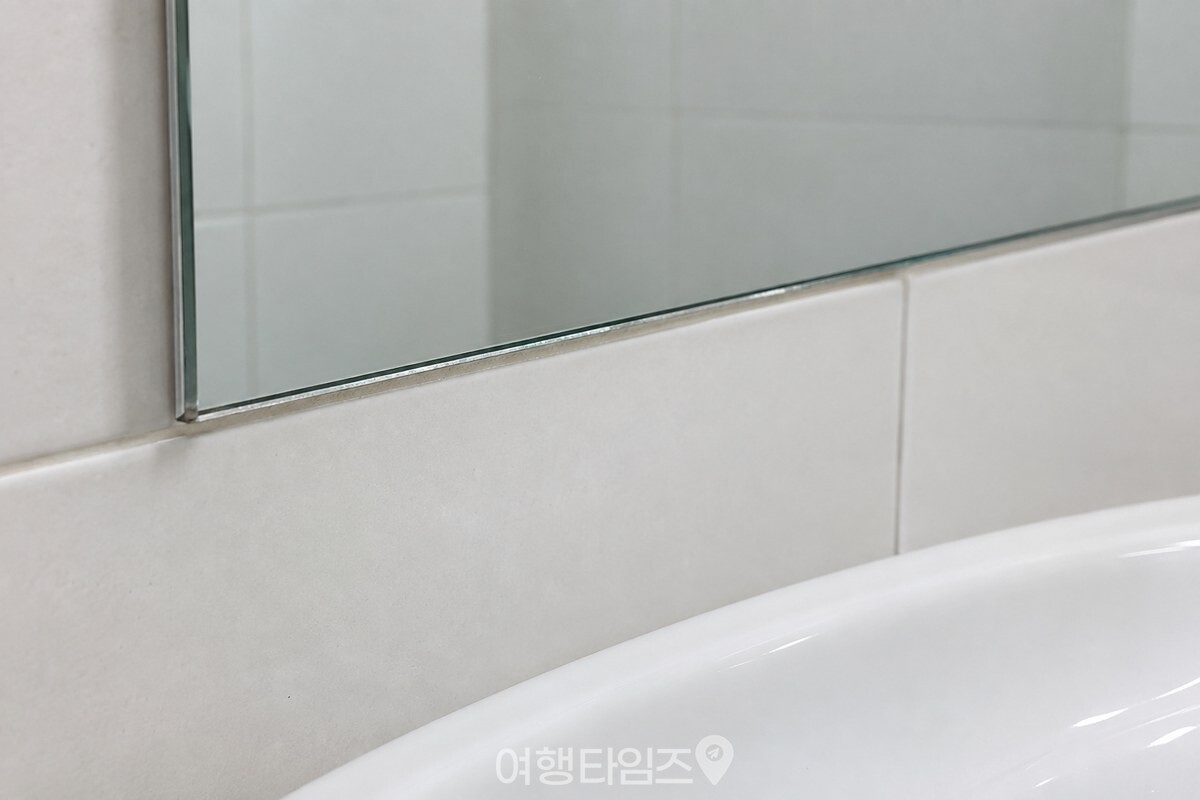 욕실 거울의 잘린 아래쪽 가장자리와 벽 사이의 좁은 틈을 가까이에서 본 모습 / 기사 이해를 돕기 위한 생성형 이미지
