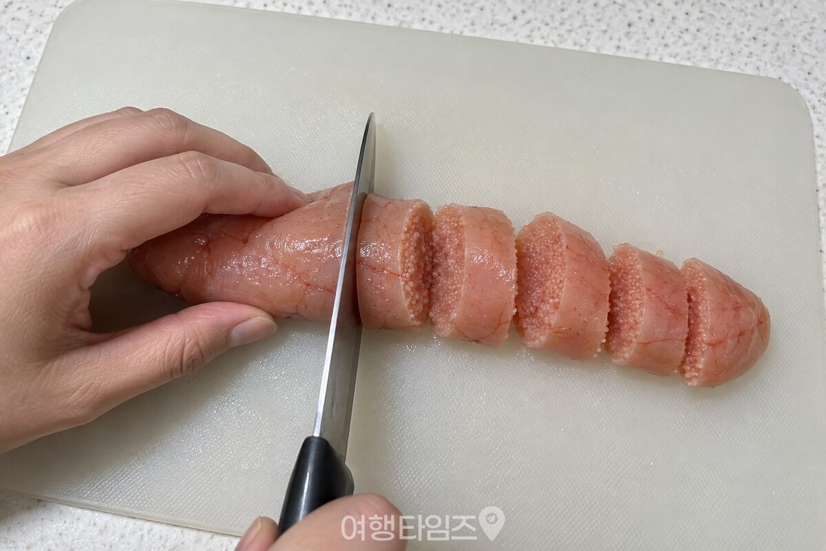 도마 위에서 중간 크기 명란 한 덩이를 두툼한 다섯 조각으로 써는 손. / 기사 이해를 돕기 위한 생성형 이미지