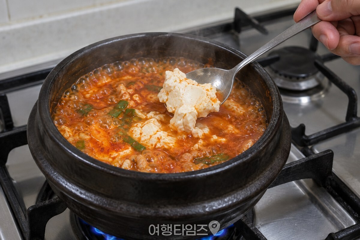 큰 숟가락으로 순두부를 끓는 붉은 국물에 조심스럽게 넣는 장면. / 기사 이해를 돕기 위한 생성형 이미지