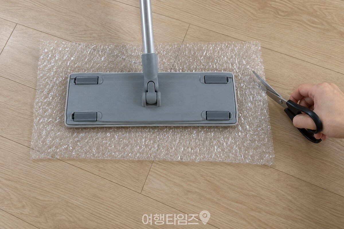 밀대 패드보다 사방으로 여유를 두고 투명 뽁뽁이를 가위로 자르는 모습. / 기사 이해를 돕기 위한 생성형 이미지