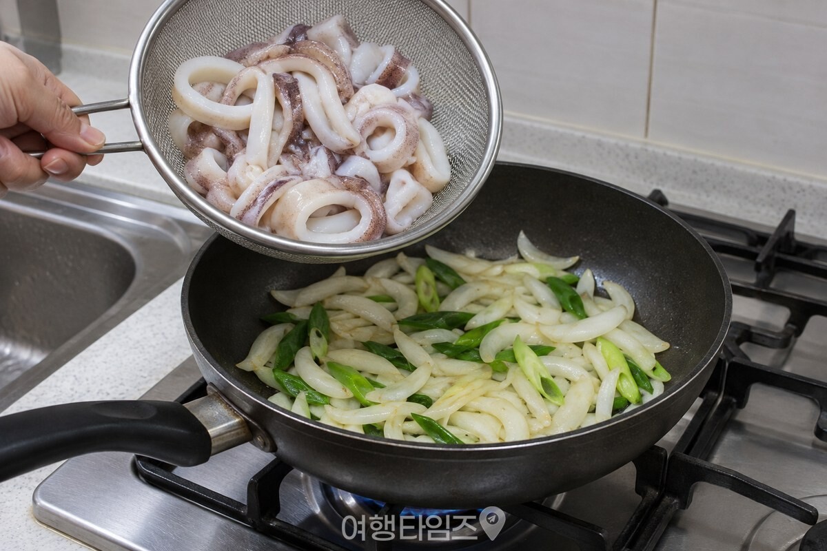 체에 밭쳐 물기를 뺀 손질 오징어가 양파와 대파를 볶은 팬에 들어갈 차례다. / 기사 이해를 돕기 위한 생성형 이미지