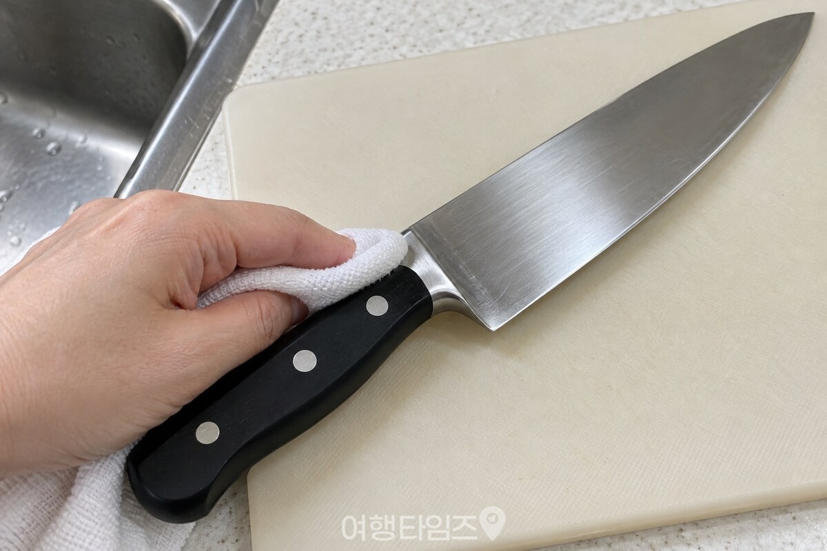 금속 못이 있는 칼 손잡이의 연결부를 행주 끝으로 눌러 닦는 모습. / 기사 이해를 돕기 위한 생성형 이미지