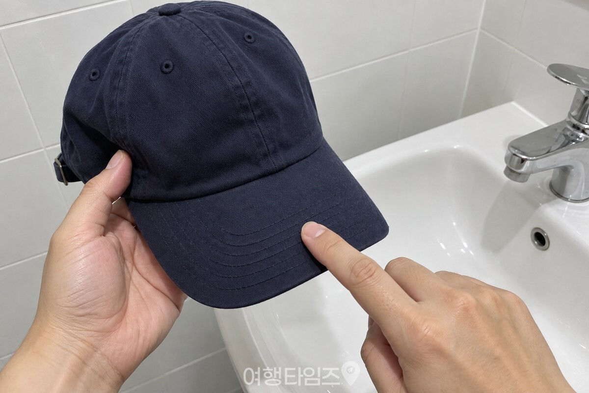 세면대 옆에서 챙 가운데를 손가락 끝으로 가볍게 두드려 보는 야구모자 모습. / 기사 이해를 돕기 위한 생성형 이미지