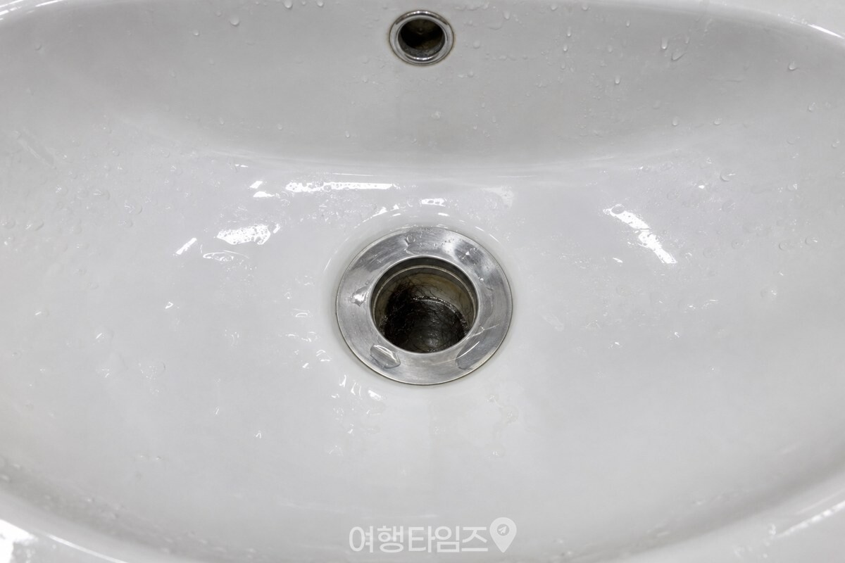 세면대 배수구 입구 아래쪽에 머리카락이 엉켜 물길을 좁힌 모습을 보여 주는 장면 / 기사 이해를 돕기 위한 생성형 이미지
