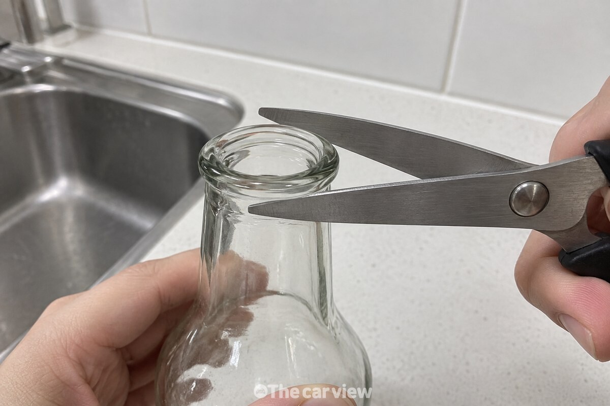 둥글게 말린 유리병 입구를 가위 날의 안쪽으로 물린 가까운 모습. / 기사 이해를 돕기 위한 생성형 이미지