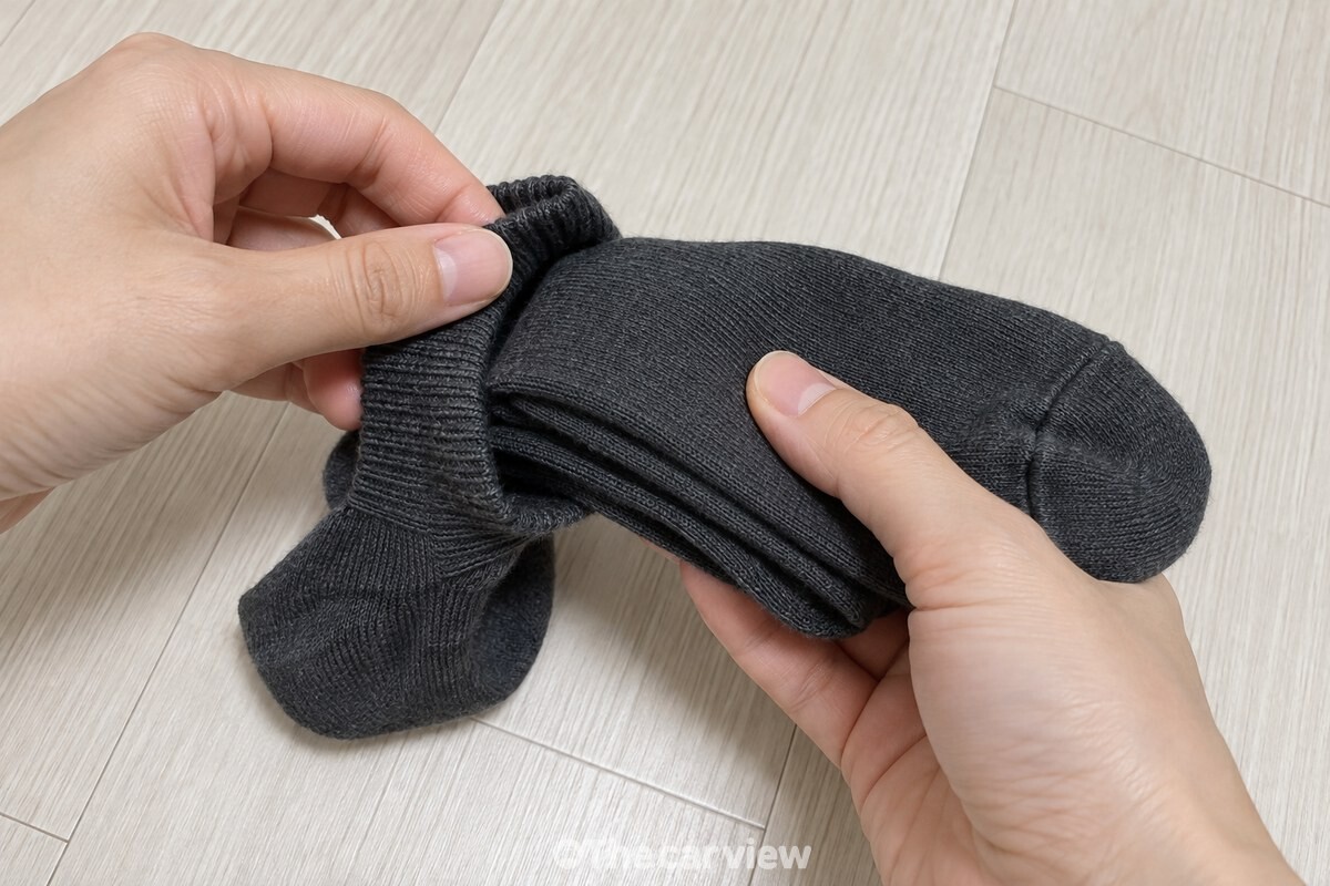 양손 엄지로 발목 입구를 벌려 세 겹으로 접은 끝을 넣는 모습. / 기사 이해를 돕기 위한 생성형 이미지