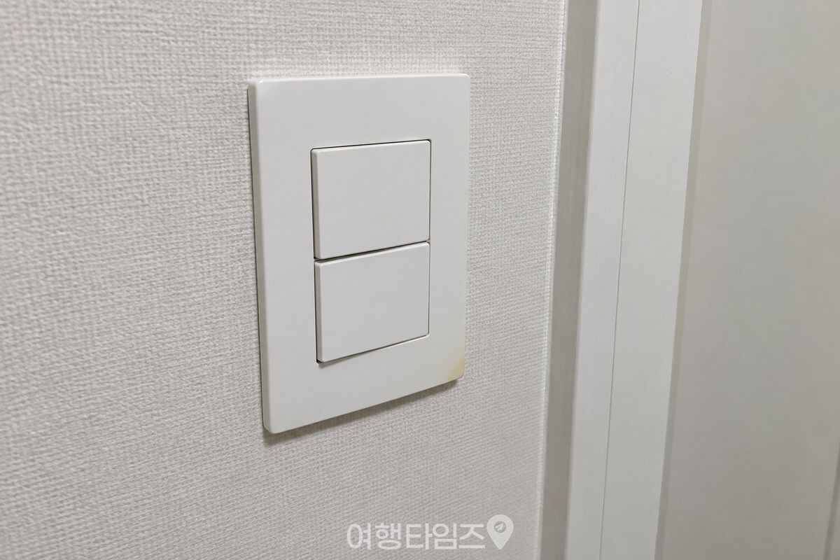 흰 벽의 스위치 커버 테두리에 남은 옅은 누런 변색을 가까이에서 보여 준다. / 기사 이해를 돕기 위한 생성형 이미지